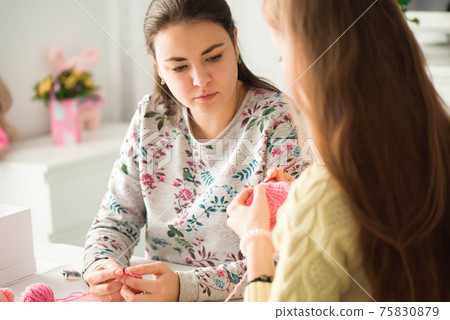 Young attractive girls in a knitting lesson Young attractive girls in a knitting lesson 75830879