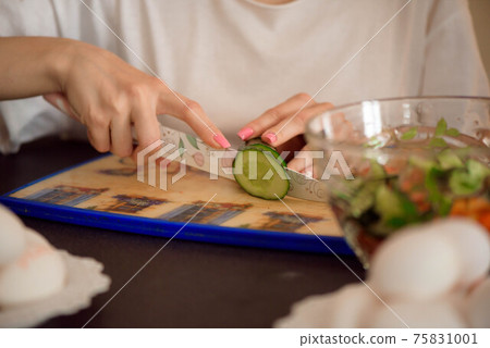 Young girlfriends chopping vegetables with twin in a family home kitchen. 75831001