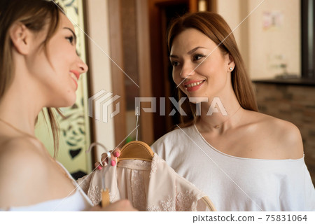 woman choosing clothes in front of full closet. 75831064