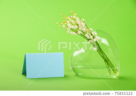 Lilly of the valley in heart shaped vase on green Lilly of the valley in heart shaped vase on green 75831122