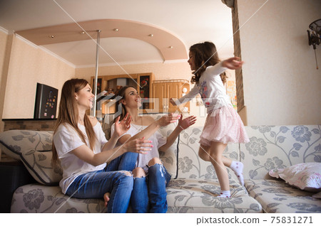 Happy sisters playing and having fun in the livingroom. Family at home. 75831271