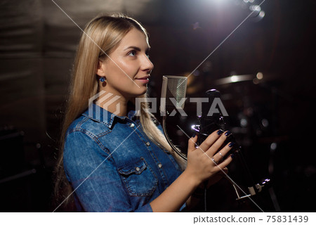Female singer singing a song. Woman performing in a recording st Female singer singing a song. Woman performing in a recording st 75831439