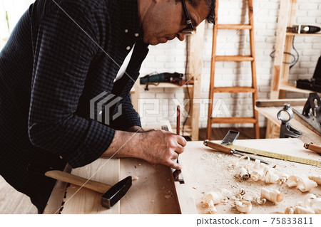 Carpenter makes pencil marks on a wood plank 75833811