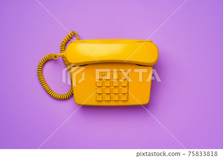 Yellow landline telephone on purple background close up 75833818