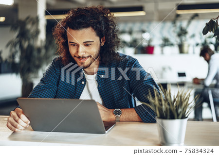 Young businessman, successful freelancer working online on computer, sitting in modern office 75834324
