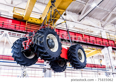 Big tractor wheels installation at assembly room at industrial plant Big tractor wheels installation at assembly room at industrial plant 75835062