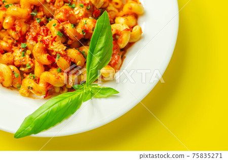 Cooked cellentani pasta with cooked chicken breast and peppers in a spicy tomato and jalapeno dressing Cooked cellentani pasta with cooked chicken breast and peppers in a spicy tomato and jalapeno dressing 75835271