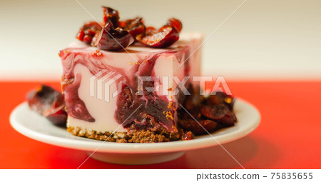 Japanese cheesecake with cherry sauce and fresh cherries on the ceramic plate and red background 75835655
