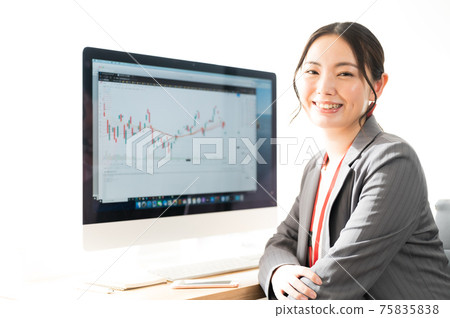 在TradingView提供的股票圖表屏幕前微笑的女性交易員 在TradingView提供的股票圖表屏幕前微笑的女性交易員 75835838