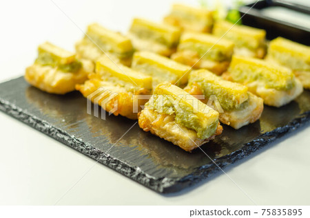 Skinless and boneless battered Alaska Pollock fillet pieces, topped with mushy peas and fried potato 75835895