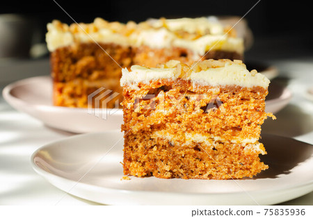 Sliced carrot cake filled and topped with cream cheese buttercream and decorated with walnuts 75835936