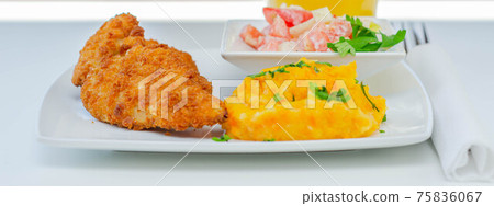 Breaded and herbed chicken breast fillet served with mashed carrots with potatoes  and  tomato salad with onions 75836067