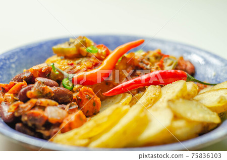 Chicken breast fillet with a chilli and cheese tomato sauce with crispy potato slices and minty bean salad on a blue plate 75836103