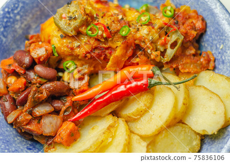 Chicken breast fillet with a chilli and cheese tomato sauce with crispy potato slices and minty bean salad on a blue plate Chicken breast fillet with a chilli and cheese tomato sauce with crispy potato slices and minty bean salad on a blue plate 75836106