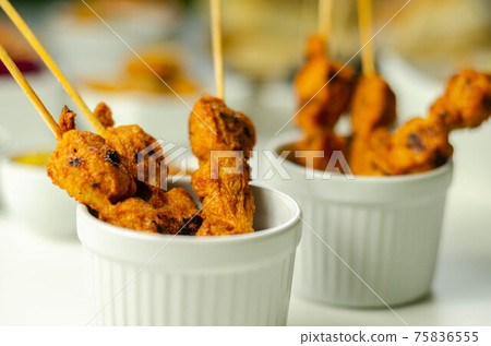 Satay chicken breast marinated in Indonesian style spices and grill on wooden skewers with dip peanut, ketchup, mustard Satay chicken breast marinated in Indonesian style spices and grill on wooden skewers with dip peanut, ketchup, mustard 75836555