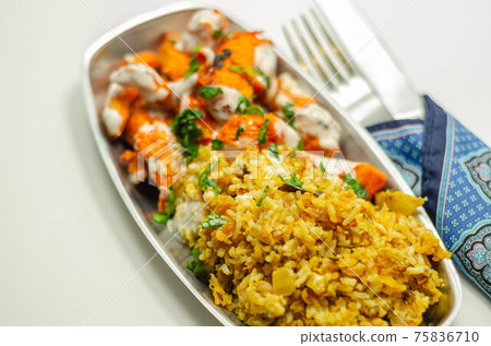 Pieces of cooked marinated chicken breast in an onion and tomato sauce with yogurt and mint and crispy fried onions layered with spiced basmati rice 75836710