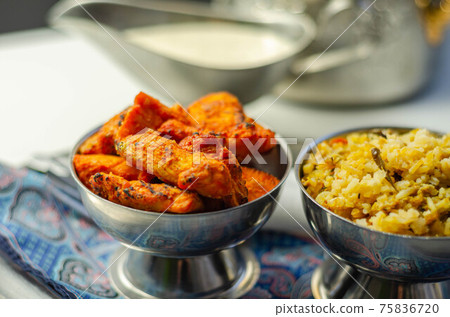 Pieces of cooked marinated chicken breast in an onion and tomato sauce with yogurt and mint and crispy fried onions layered with spiced basmati rice 75836720