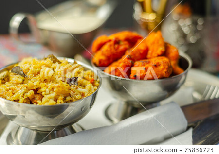 Pieces of cooked marinated chicken breast in an onion and tomato sauce with yogurt and mint and crispy fried onions layered with spiced basmati rice Pieces of cooked marinated chicken breast in an onion and tomato sauce with yogurt and mint and crispy fried onions layered with spiced basmati rice 75836723