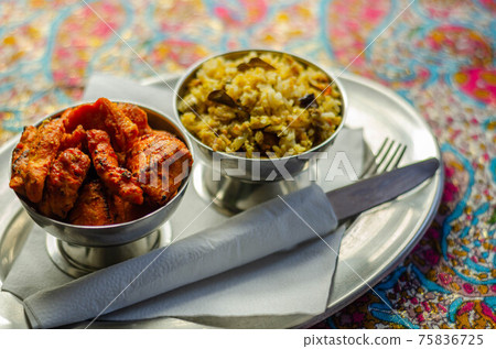 Pieces of cooked marinated chicken breast in an onion and tomato sauce with yogurt and mint and crispy fried onions layered with spiced basmati rice 75836725