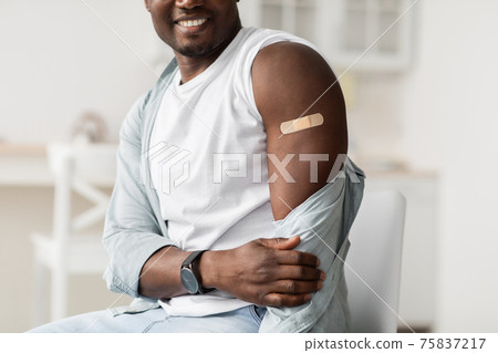 Unrecognizable african american man showing plaster after coronavirus vaccine shot in the shoulder 75837217