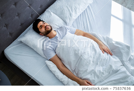 Unhappy arab man having insomnia unable to sleep, lying in bed, looking up and contemplating, copy space Unhappy arab man having insomnia unable to sleep, lying in bed, looking up and contemplating, copy space 75837636