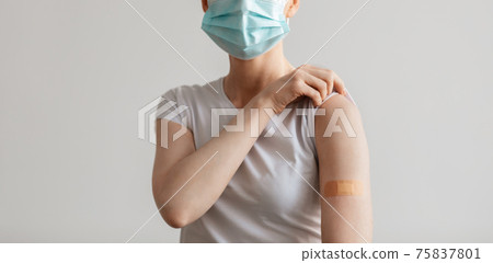 Adult woman in protective mask with band aid on hand on vaccination place Adult woman in protective mask with band aid on hand on vaccination place 75837801