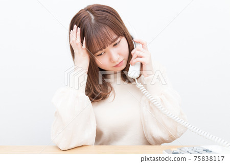 一個女人在座機上講話時擔心 一個女人在座機上講話時擔心 75838117