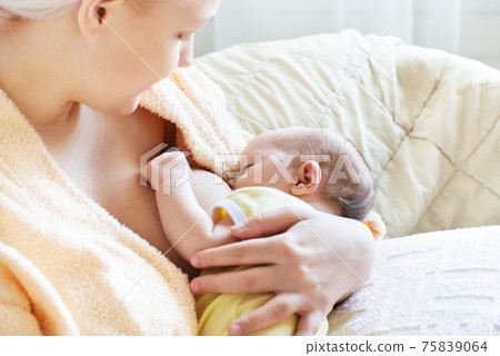 Baby eating breast milk. Caucasian blonde young mother breastfeeding her baby horizontal photo. Concept of lactation. 75839064