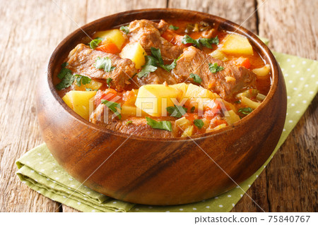 Spezzatino Italian beef with potatoes, carrots, onions and celery in a spicy sauce close-up in a bowl. horizontal 75840767