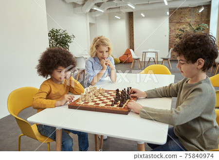 Players. Children playing chess. Little boys sitting at the table and playing in chess school Players. Children playing chess. Little boys sitting at the table and playing in chess school 75840974