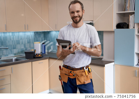 Young caucasian house master with tablet standing in kitchen Young caucasian house master with tablet standing in kitchen 75841756