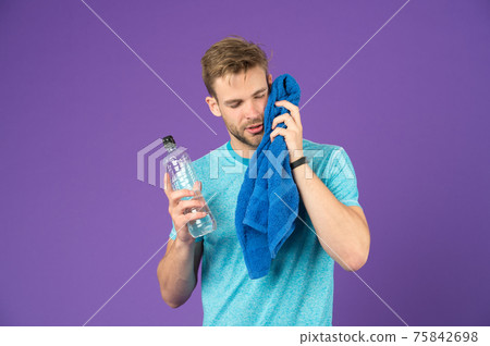 Athlete in blue tshirt and shorts with towel after training.  75842698