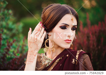Portrait of beautiful indian girl. Young hindu woman model with tatoo mehndi and kundan jewelry Portrait of beautiful indian girl. Young hindu woman model with tatoo mehndi and kundan jewelry 75842829