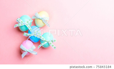Easter background pink. Colourful egg with tape ribbon on pastel pink background in Happy Easter decoration. Flat lay, top view. 75843184