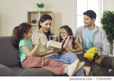 Pleasant surprised mom with happy expression opening gift box from kids Pleasant surprised mom with happy expression opening gift box from kids 75844940