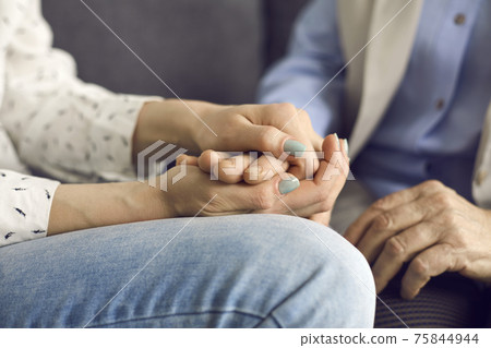 Loving young woman holding her senior mother's hand comforting and supporting her Loving young woman holding her senior mother's hand comforting and supporting her 75844944