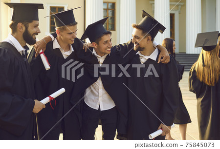 Group of happy boys students university graduates mates standing and hugging with diplomas in hands Group of happy boys students university graduates mates standing and hugging with diplomas in hands 75845073
