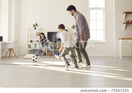 Mother trying to catch soccer ball having fun with adorable family at home 75845105