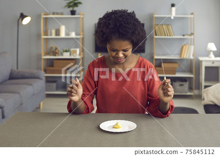 African american woman with disgusting grimace looking at apple piece on plate African american woman with disgusting grimace looking at apple piece on plate 75845112