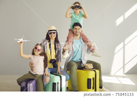 Happy laughing family with kids sitting on vacation suitcases isolated portrait Happy laughing family with kids sitting on vacation suitcases isolated portrait 75845133