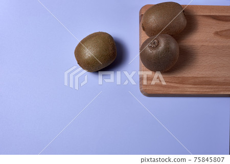Three kiwis on wooden board on blue mat Three kiwis on wooden board on blue mat 75845807
