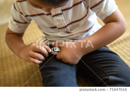 A boy who cuts his nails. 75847016
