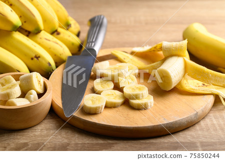 Sliced ripe banana fruit on wooden cutting board preparing for cooking Sliced ripe banana fruit on wooden cutting board preparing for cooking 75850244