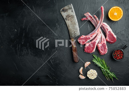 Raw fresh lamb ribs, with ingredients carrot orange, herbs, on black stone background, top view flat lay , with copyspace and space for text 75852883