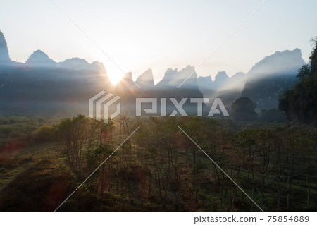 Aerial view of beatiful sunrise over karst mountain peak landscape Aerial view of beatiful sunrise over karst mountain peak landscape 75854889