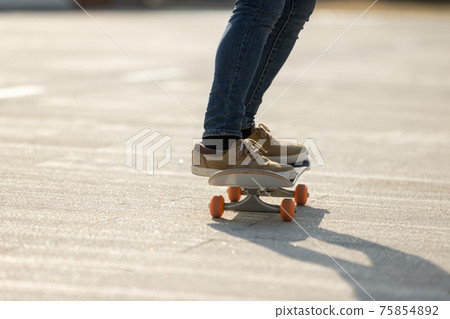Skateboarder skateboarding outdoors on sunny morning Skateboarder skateboarding outdoors on sunny morning 75854892