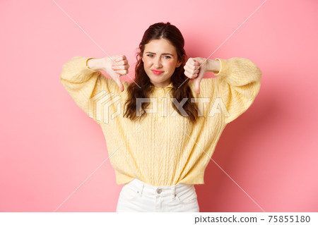 Very bad. Disappointed young woman complaining on something awful, showing dislike with thumbs down, grimacing and frowning, shaking head, give negative feedback, pink background Very bad. Disappointed young woman complaining on something awful, showing dislike with thumbs down, grimacing and frowning, shaking head, give negative feedback, pink background 75855180