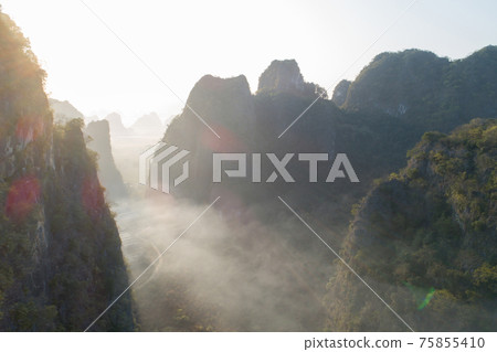 Aerial view of beatiful sunrise over karst mountain peak landscape Aerial view of beatiful sunrise over karst mountain peak landscape 75855410