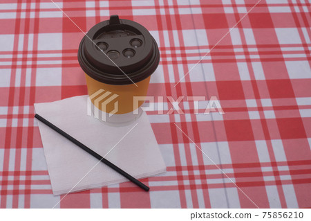 Yellow disposable glass of coffee with a straw and a napkin. Yellow disposable glass of coffee with a straw and a napkin. 75856210