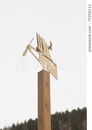 Wooden weather vane with a propeller on a wooden post. Wooden weather vane with a propeller on a wooden post. 75856212